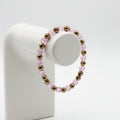 A beaded stretch bracelet made of pink faceted beads and metallic bronze spacer beads, displayed on a textured beige fabric background.